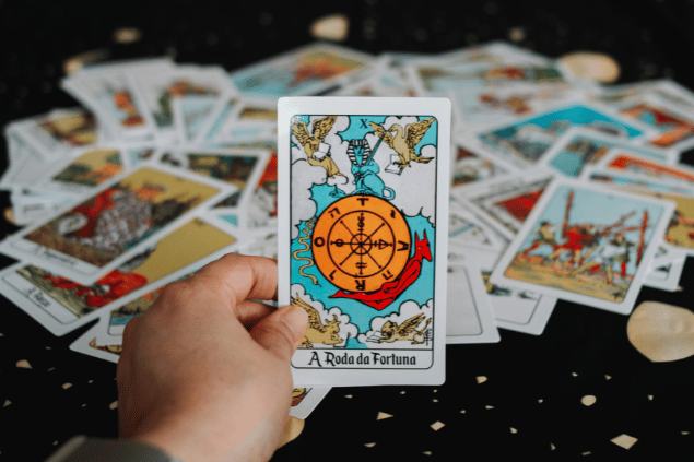 A mão de uma pessoa segura a carta de Tarot 