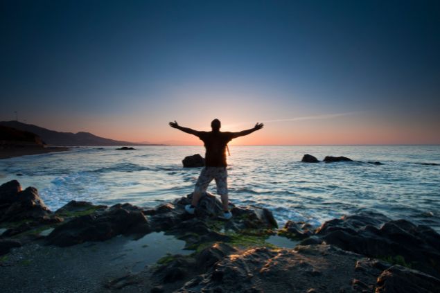 jgrisquez de Getty Images no Canva Homem na praia de braços abertos