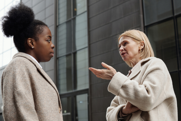 Duas mulheres conversando em frente a um prédio