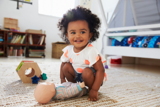 Bebê brincando com uma boneca em cima de um tapete
