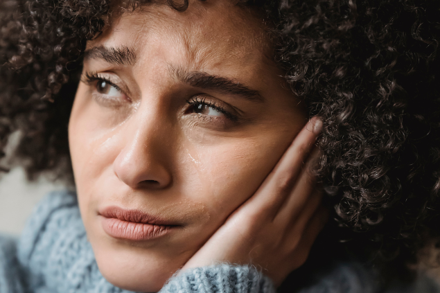 Mulher chorando enquanto apoia a cabeça em sua mão esquerda