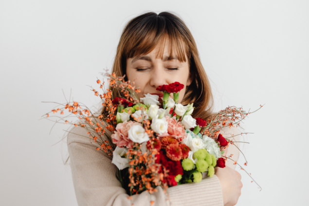 Mulher de olhos fechados segurando um buque de flores