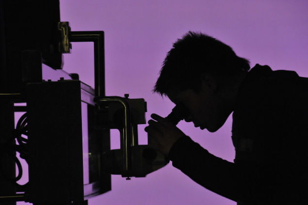 Cientista olhando por um microscópio 