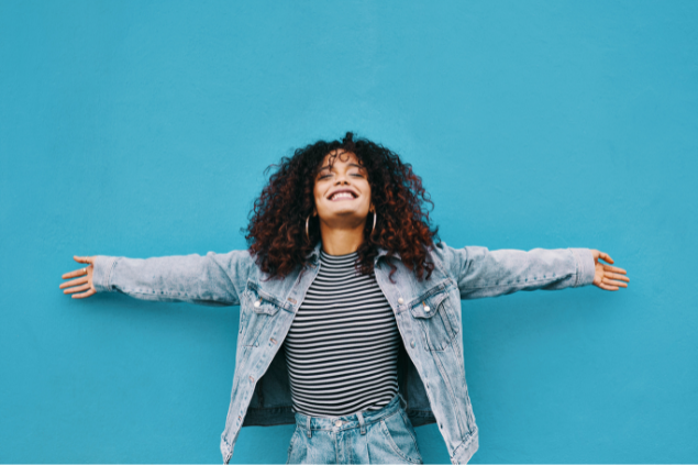 Mulher negra sorrindo com os braços abertos