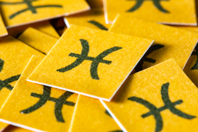 Papéis amarelos cortados em quadrados com o símbolo de peixes