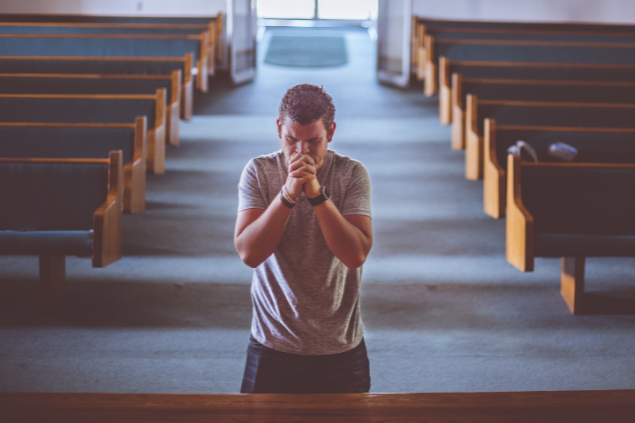 Homem orando na igreja, de joelhos no altar