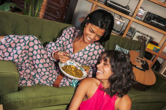 Duas mulheres se divertindo sentadas no sofá