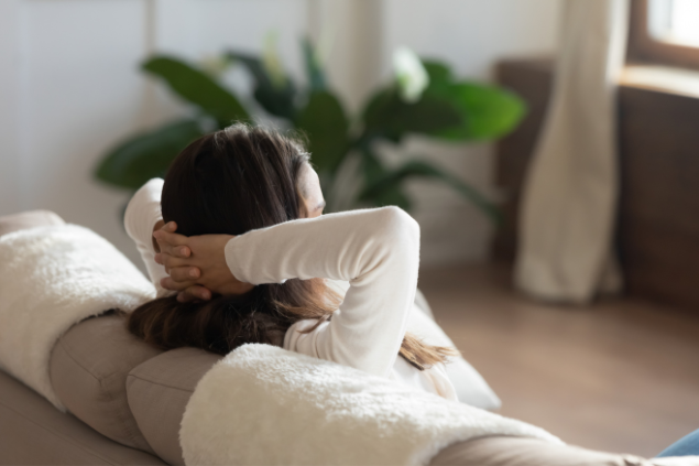 Mulher deitada no sofá com os braços na cabeça