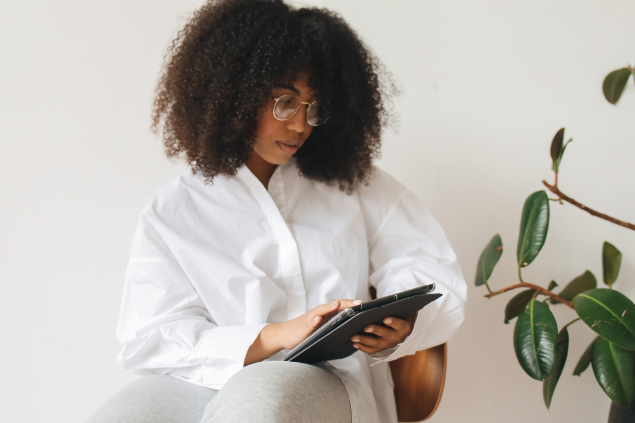Mulher negra sentada mexendo em um tablet