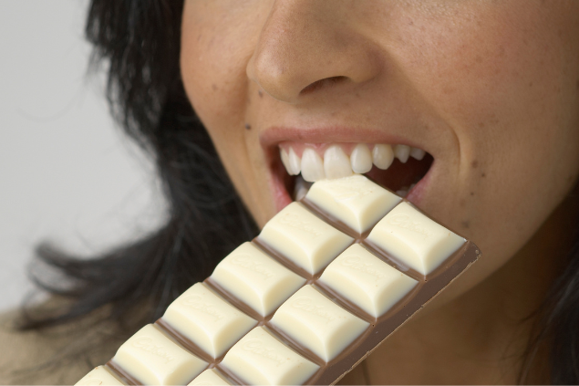 Mulher mordendo uma barra de chocolate branco