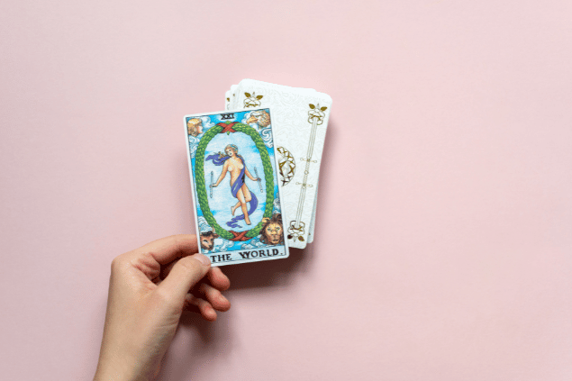 A mão de uma pessoa segurando a carta de Tarot 