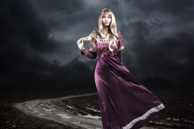 Imagem de uma mulher loura de cabelos longos, usando um vestido longo na cor roxa, simbolizando a pombagira Dama da Noite.