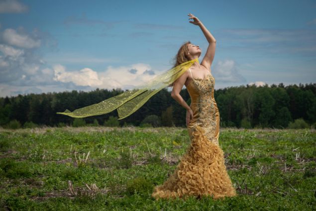 Imagem de uma linda e elegante mulher, usando um vestido dourado com um lenço no pescoço, simbolizando a entidade Maria do Cais.
