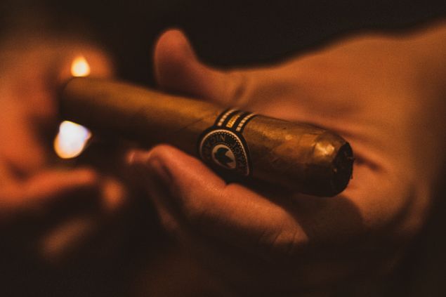 Imagem da mão de um homem, segurando um charuto, um dos itens de oferenda para a entidade Zé Malandro.