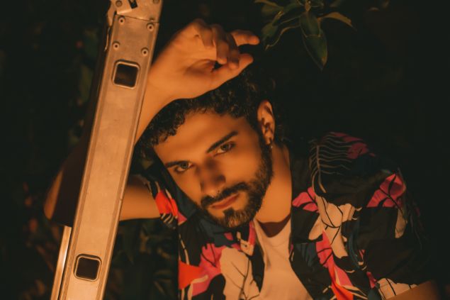 Imagem de um homem com cabelos enrolados, usando uma camisa florida e um brinco de argola em uma das orelhas. Ele está simbolizando o cigano Wladimir da Umbanda.