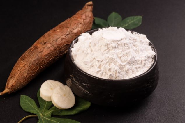 Sri Widyowati de Sri Widyowati / Canva Imagem de um bowl contendo farinha de mandioca. Ao lado, uma mandioca com casca, folhas do legume, completam os elementos da foto, simbolizando uma das oferendas para o Exu Gato Preto.