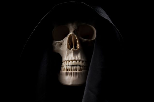 Videologia / Getty Images / Canva Imagem da ossada de um crânio usando uma capa preta, simbolizando o Exu da Morte.