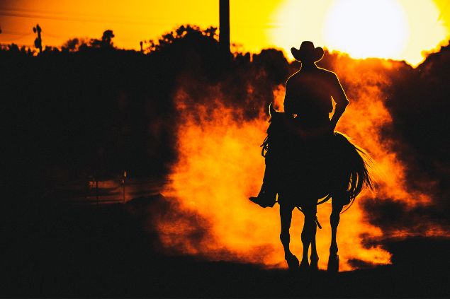 Peeterv / Getty Images Signature / Canva Imagem de um homem montado em um cavalo, em uma tarde com um lindo pôr do Sol, simbolizando a entidade João Boiadeiro na Umbanda.