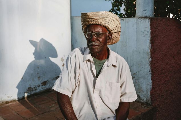 Mehmet Turgut Kirkgoz / Pexels / Canva Imagem de um homem idoso, negro, usando uma camisa branca e um chapéu na cabeça, simbolizando o Pai João na Umbanda.