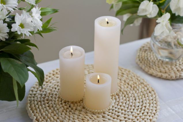 Moniamar / Getty Images / Canva Imagem de três velas brancas acesas em um altar, simbolizando uma das oferendas para o Pai João da Umbanda.