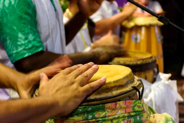 Imagem de várias pessoas em um terriero, tocando atabaques e outros instrumentos, durante uma sessão de gira para a cabocla Jarina da Umbanda.