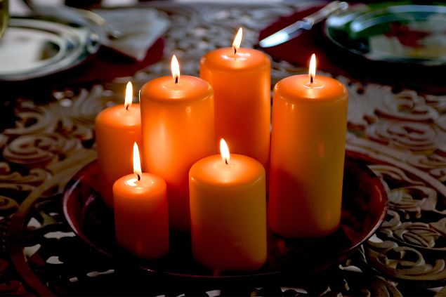 Sdart / Getty Images Signature / Canva Imagem de seis velas acesas na cor laranja, simbolizando uma oferenda para o Exu Gira Mundo da Umbanda.