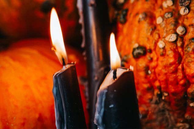 Bilder von YuM / Canva Imagem de fundo vermelho e em destaque duas velas acesas na cor preta, simbolizando uma oferenda para o Exu 7 Encruzilhadas.