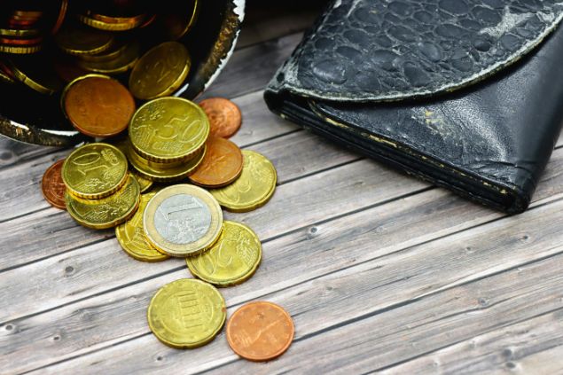 Marta Branco / Pexels / Canva Imagem de várias moedas sobre uma mesa de madeira, simbolizando uma das oferendas para a Pombagira Maria Quitéria da Umbanda.