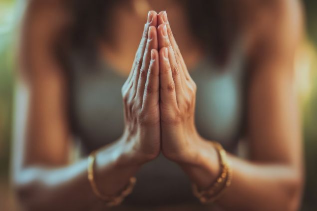 Imagem das mãos de uma mulher, em posição de oração.