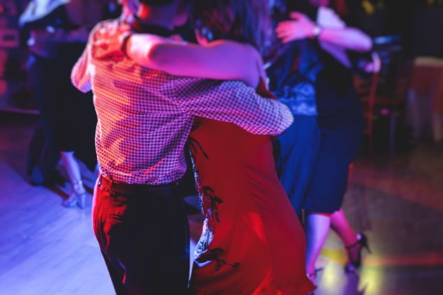 Imagem de um casal dançando salsa em um salão juntamente com outros casais.