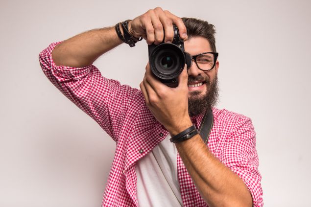 GeorgeRudy / Getty Images / Canva Imagem de um homem fotógrafo segurando um câmera fotográfica.