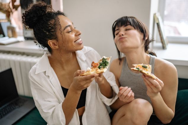 Yan Krukau / Pexels / Canva Imagem de duas moças jovens comendo pizza com as mãos, representando o signo de touro.