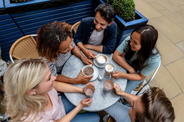 Andresr de Getty Images Signature Imagem de várias pessoas reunidas em um café conversando. Elas representam o signo de gêmeos.