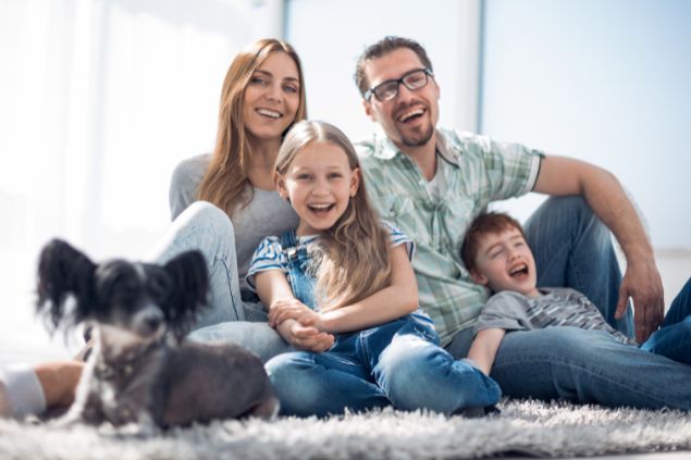 Edhar / Getty Images Pro / Canva Imagem de uma famlília feliz, reunida em uma sala de estar. Todos estão sentados em um tapete, simbolizando o signo de câncer.