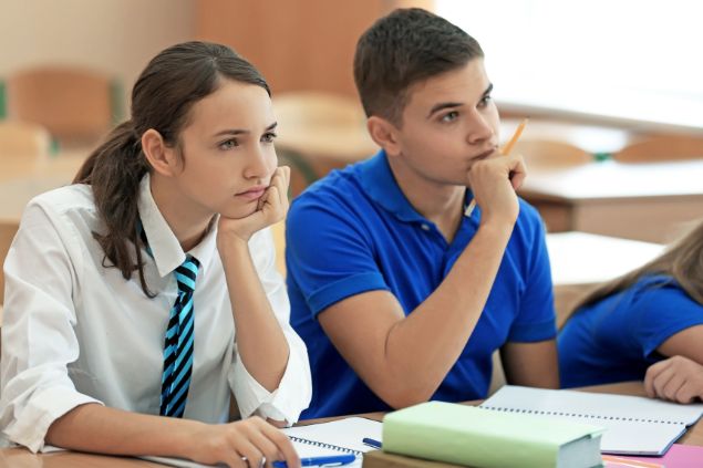 Imagem de um casal de alunos do signo de leão em uma sala de aula.