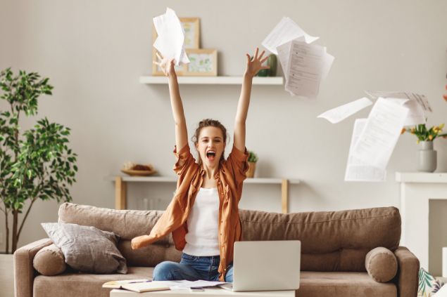 evgenyatamanenko de Getty Images grátis para o Canva Pro Imagem de uma mulher sentada no sofá lendo os roteiros de sua personagem. Ela joga vários papéis para cima.