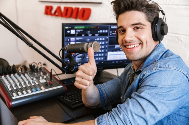 Dean Drobot / Canva Imagem de um radialista em sua mesa de trabalho dentro da rádio.