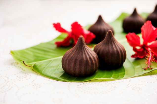 Subodhsathe / Getty Images / Canva Imagem de uma oferenda de doces para os Erês, feita com folha de bananeira e uma flor vermelha de hibisco.