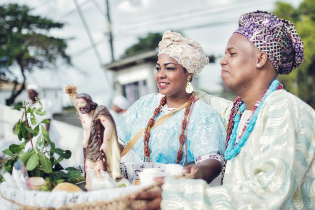 Golero / Getty Images Signature / Canva Imagem de um casal de baianos segurando uma oferenda durante uma cerimônia religiosa em Salvador.