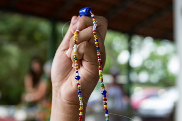 Imagem de uma mão segurando uma guia, durante uma sessão de passe na Umbanda.