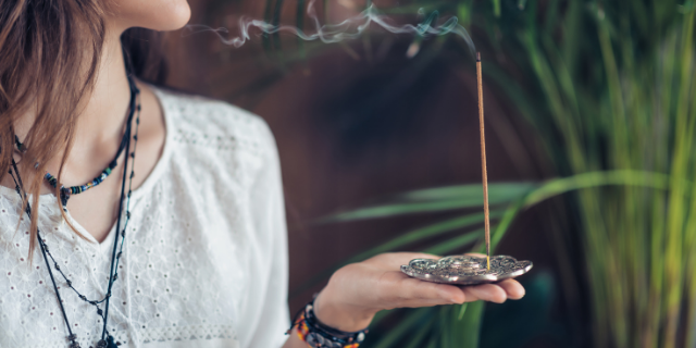 microgen / Canva Mulher segura incensário; sobre ele, há um incenso aceso.