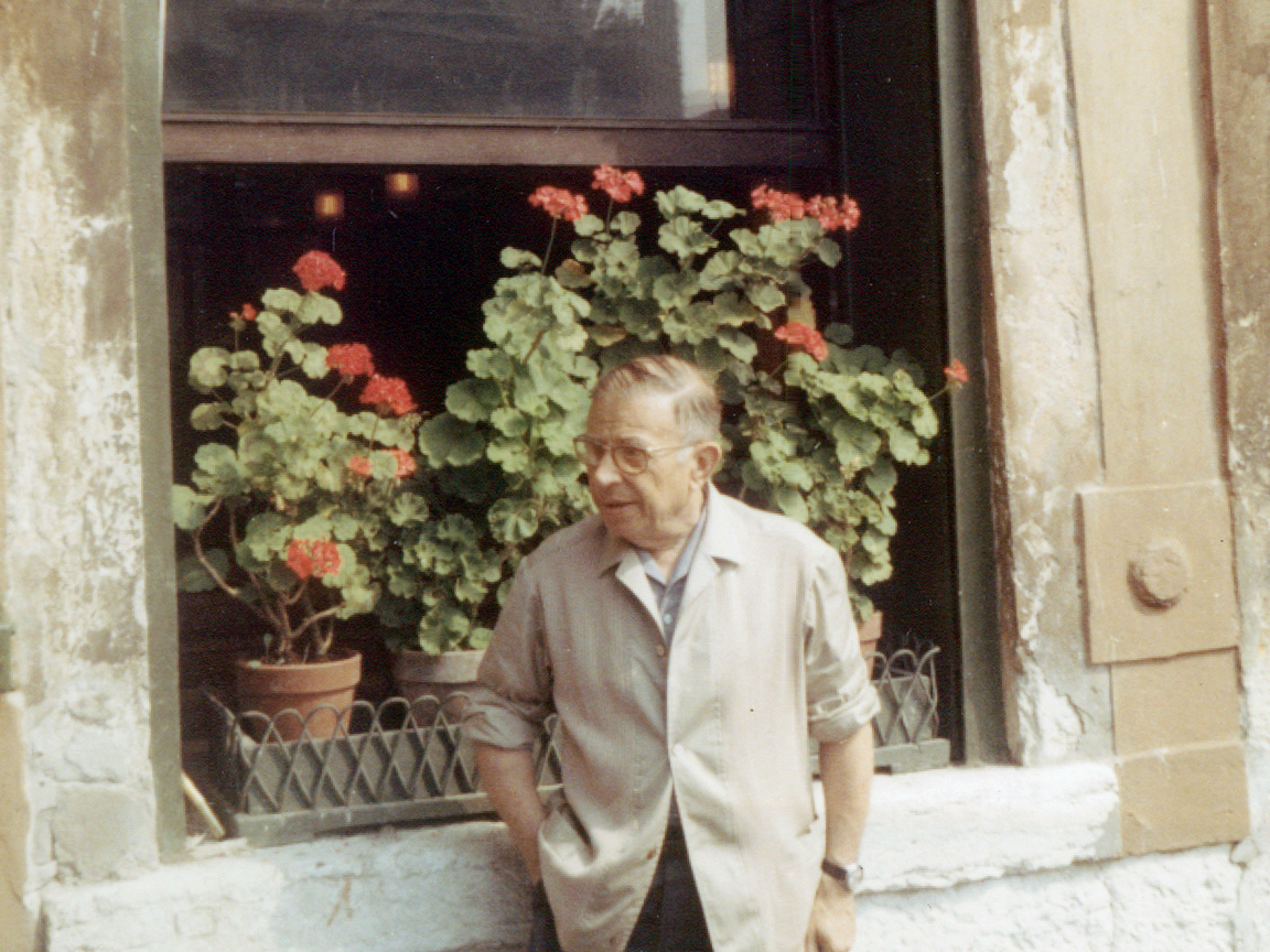 Jean-Paul Sartre ao lado de uma janela com flores