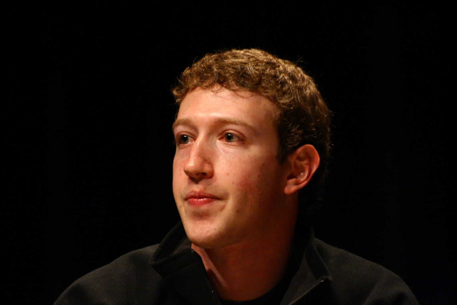 Mark Zuckerberg em um ambiente escuro olhando para o lado