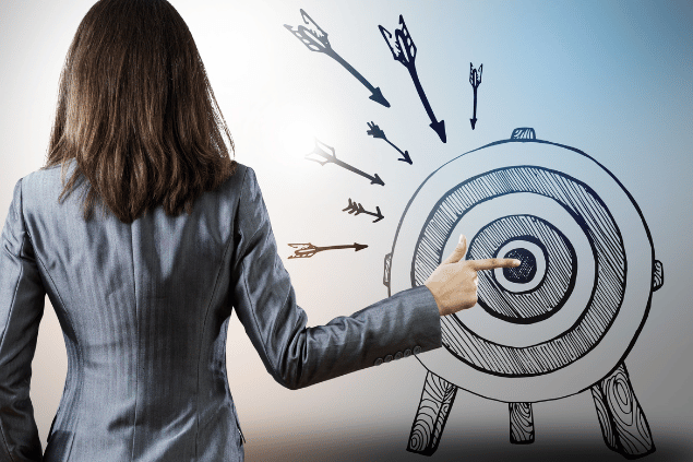 SergeyNivens / Getty Images / Canva Pro Mulher indicando para flechas o centro do arco.