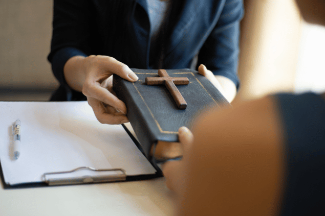 Puwadon Sang-ngern's Images / Canva Pro Mãos femininas entregando bíblia para uma mulher.