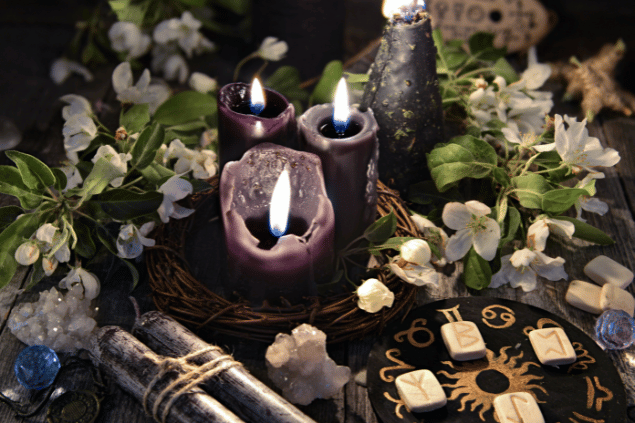 Vera Petruk / Canva Na imagem, há velas, flores e pedras em cima de uma mesa.