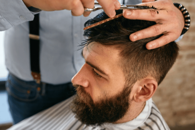 Cabelereiro cortando cabelo de um homem. 