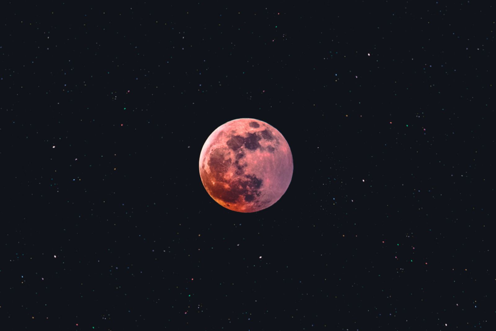 Foto de uma lua cheia em meio a estrelas.