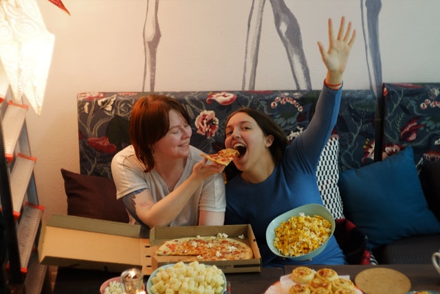 Amigas comendo pizza em sala de estar