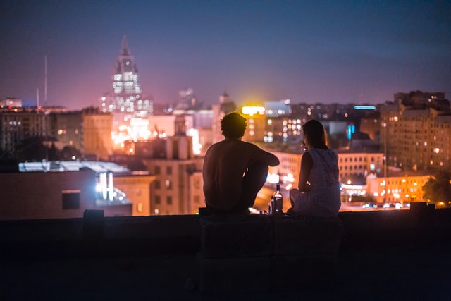 Casal sentado no terraço de um prédio, à noite